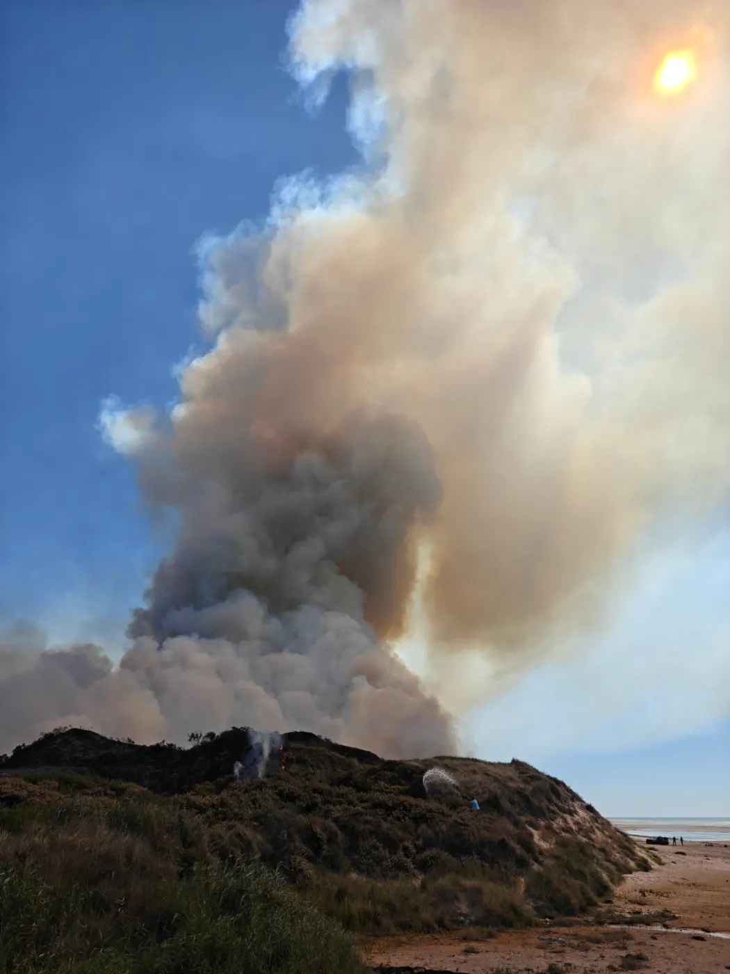 Georges Vernier arrose seul un feu dans les dunes d'Hardelot, sous un grand panache de fumée